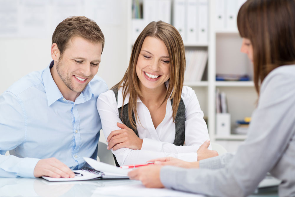 Young couple smiling with woman reviewing documents